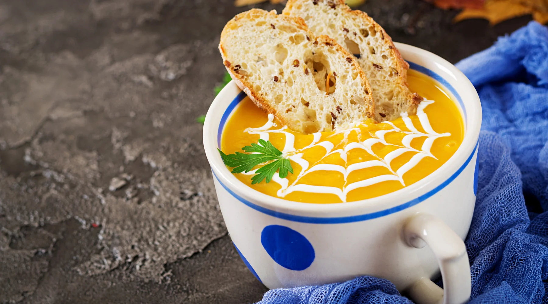 Soupe de citrouille d’Halloween décorée en toile d’araignée avec crème, servie avec tranches de pain grillé et persil frais