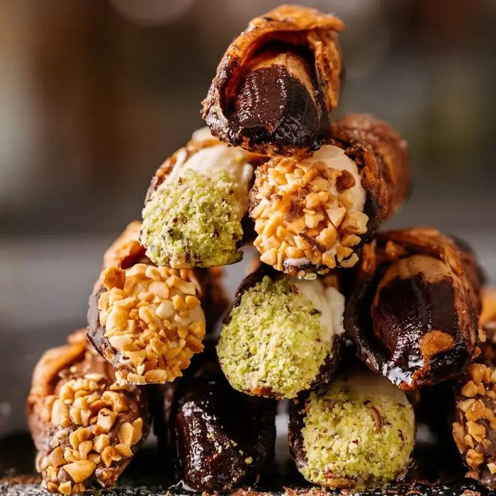 Assortiment de cannoli italiens à la pistache, au chocolat et au citron, présentés sur une assiette en céramique avec une touche artisanale sicilienne.