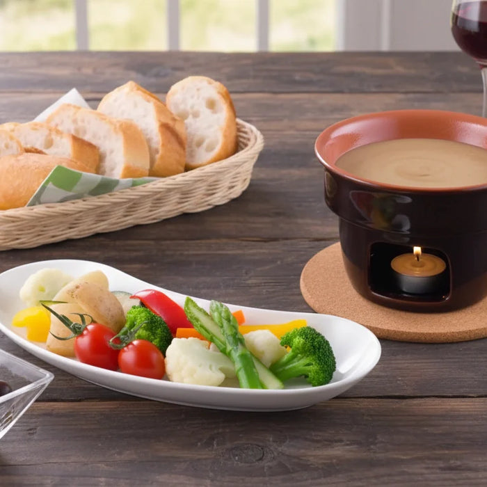 Bagna cauda piémontaise servie dans un récipient en terre cuite chauffé par une bougie, accompagnée de légumes de saison colorés, de tranches de pain, d’olives et de verres de vin rouge sur une table rustique.