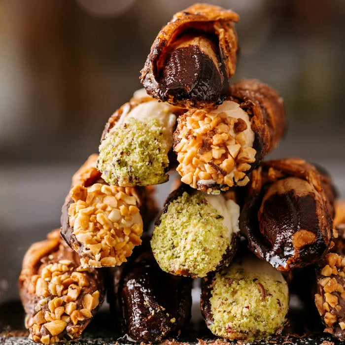 Assortiment de cannoli italiens à la pistache, au chocolat et au citron, présentés sur une assiette en céramique avec une touche artisanale sicilienne.